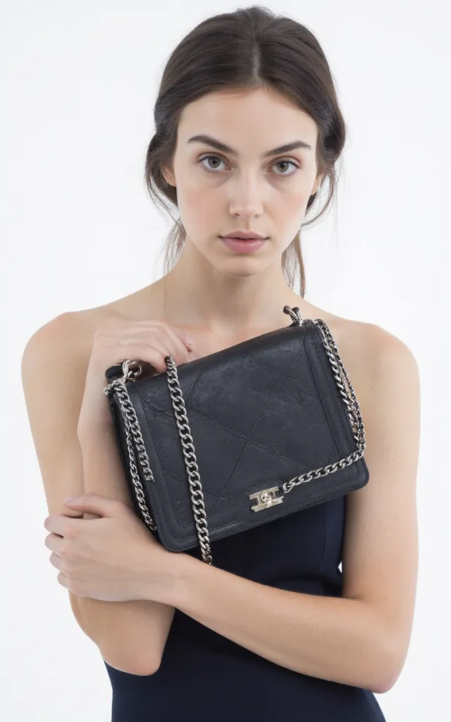 A French female model with a Chain   strap bag, wearing a dress, against a white background, in a front   facing close   up